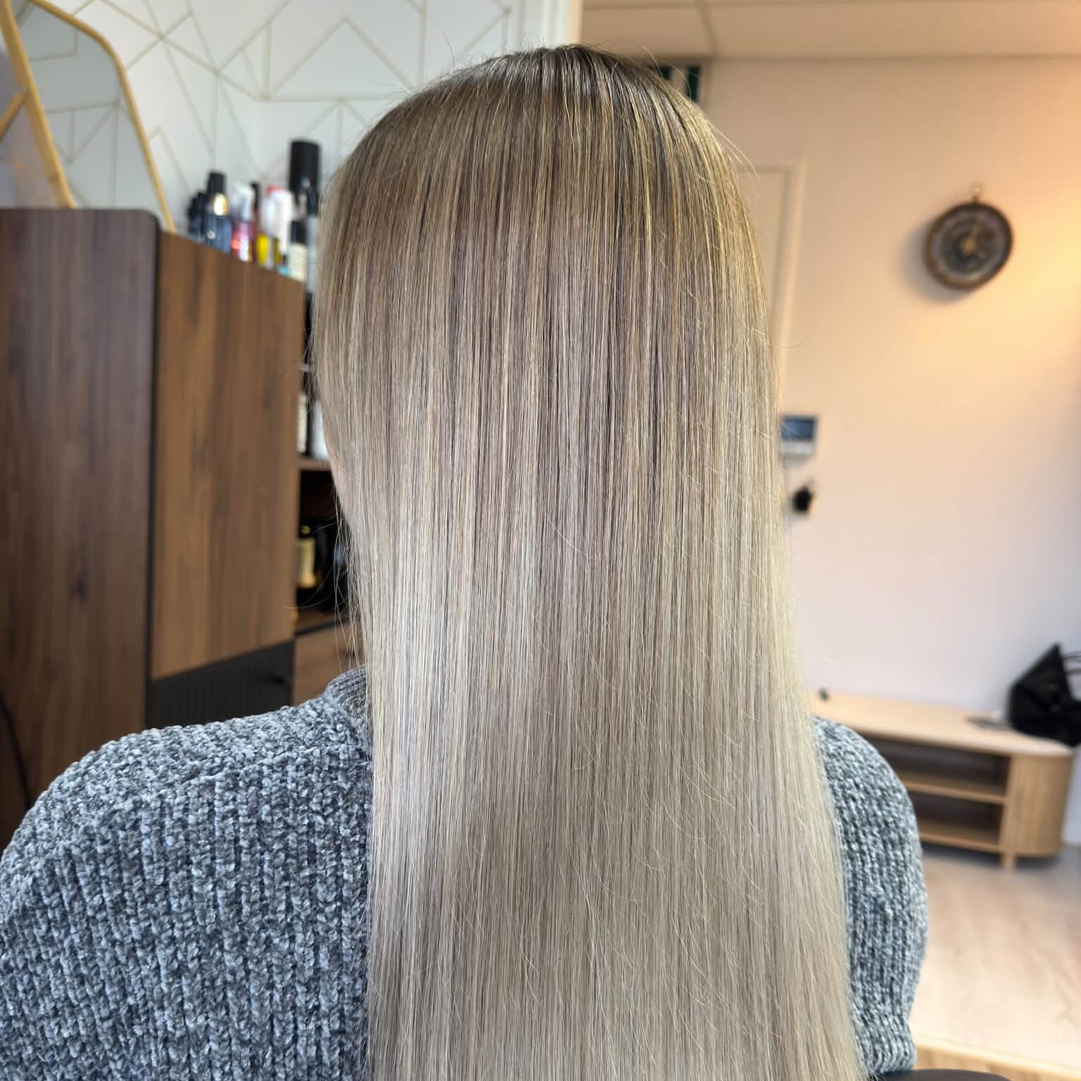 Lang, glad asblond haar van achteren, in de salon